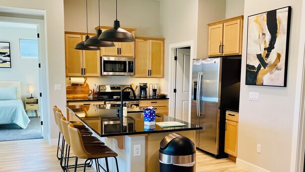 Una cocina moderna con armarios de madera, electrodomésticos de acero inoxidable y una isla central con taburetes.