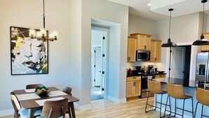 Una cocina moderna con armarios de madera, electrodomésticos de acero inoxidable y un comedor con mesa y sillas.