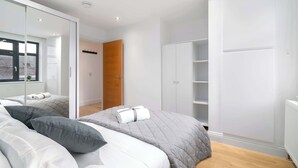 Une chambre à coucher moderne avec un lit, une armoire et un miroir.