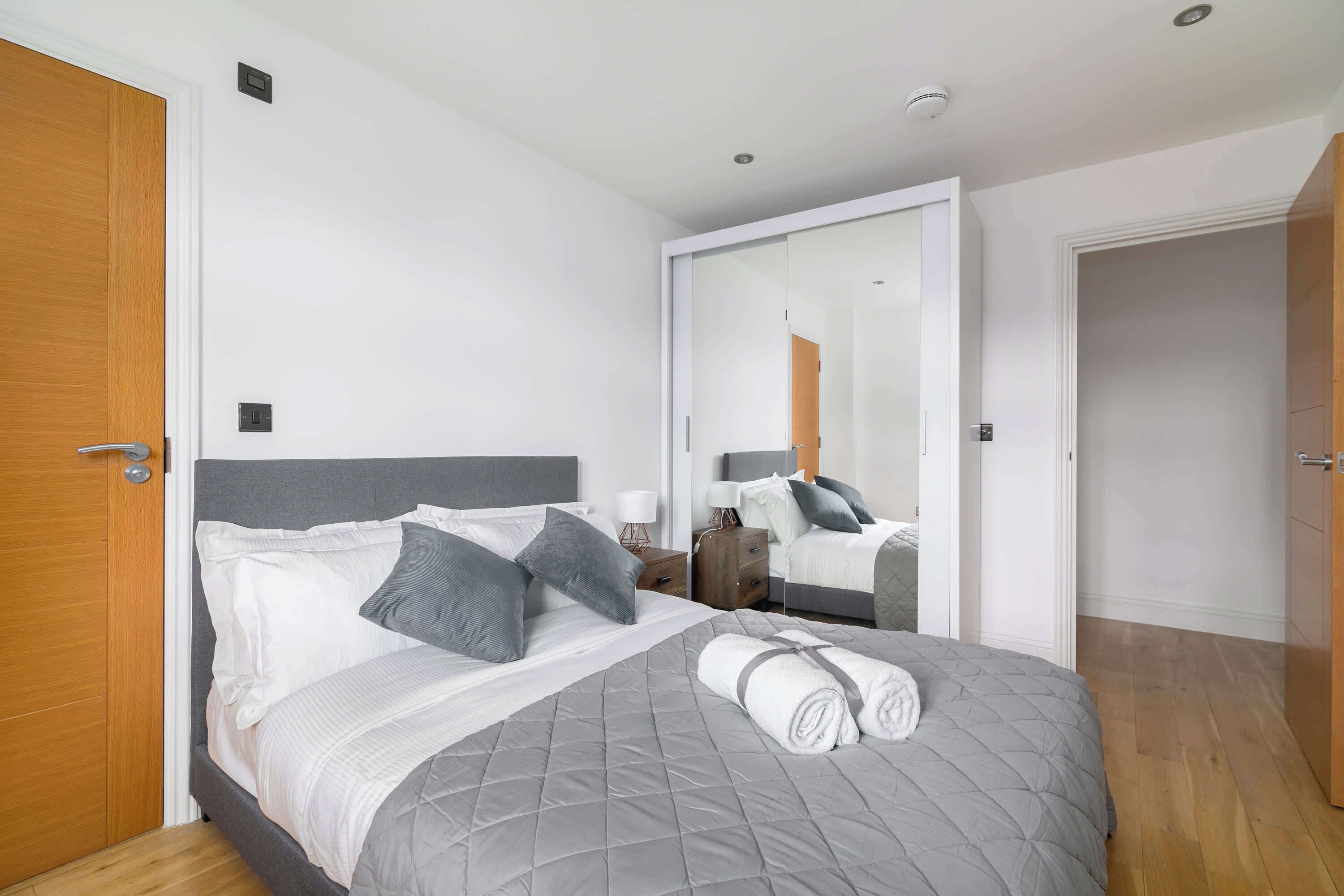 Ein Schlafzimmer mit einem Bett, einem Nachttisch, einem Spiegel und einer Tür.