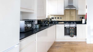 Une cuisine moderne avec des meubles blancs, un plan de travail noir et une porte de four à motifs.