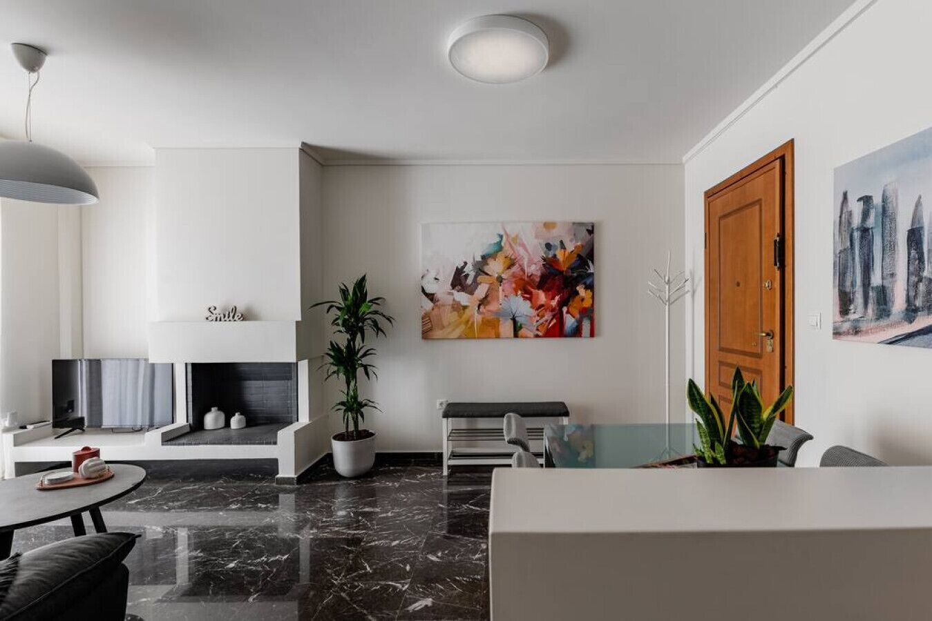 Un salon moderne doté d’une cheminée, d’un coin repas et d’un grand tableau abstrait accroché au mur.