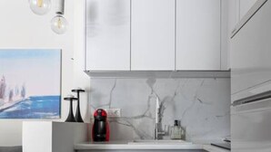 A modern kitchen with white cabinets, a marble countertop, and a black marble floor. - Beachfront apartment in Voula w/balcony (Voula)