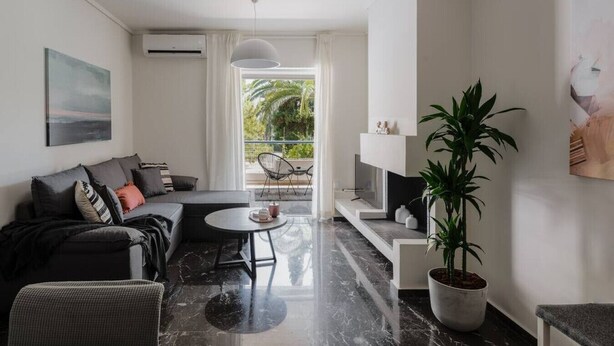 A modern living room with a sofa, a round coffee table, and a potted plant. - Beachfront apartment in Voula w/balcony (Voula)