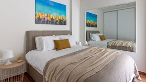 A hotel room with a large bed, a nightstand with a lamp, and a painting of flowers on the wall. - Beachfront apartment in Voula w/balcony (Voula)