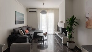 A modern living room with a sofa, a coffee table, and a TV stand. - Beachfront apartment in Voula w/balcony (Voula)