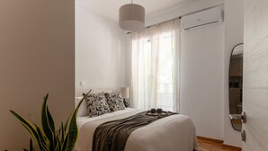 Un dormitorio con cama, mesita de noche, lámpara, equipo de aire acondicionado y espejo.