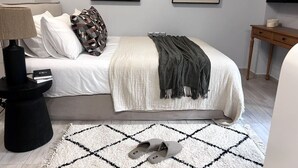 Een keurig opgemaakte slaapkamer met een bed, nachtkastje, lamp en kunstwerk aan de muur.