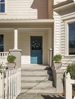 A house with a front porch, a blue door, and two potted plants on either side. - Spacious 5-bedroom Downtown home in charming Aiken (Aiken)