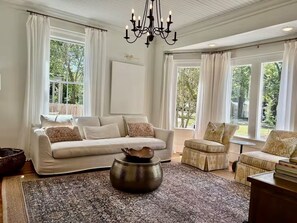 A spacious living room with a large sofa, a coffee table, and a chandelier. - Spacious 5-bedroom Downtown home in charming Aiken (Aiken)