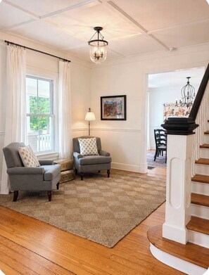 A living room with two armchairs, a rug, a lamp, a painting, and a staircase. - Spacious 5-bedroom Downtown home in charming Aiken (Aiken)