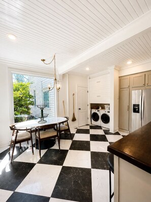 A kitchen with a checkered floor, a dining area with a table and chairs, a washing machine, and a refrigerator. - Spacious 5-bedroom Downtown home in charming Aiken (Aiken)