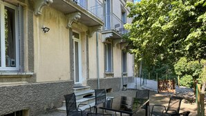 An outdoor seating area with a table and chairs in front of a building with a balcony. - Residence VillaBelleFleur-Apartment La Gentiane (Château-Ville-Vieille)