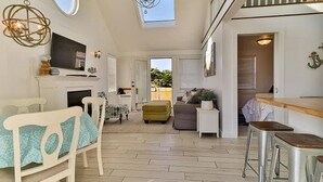 A spacious living area with a sofa, a dining table, and a kitchen area with a bar.