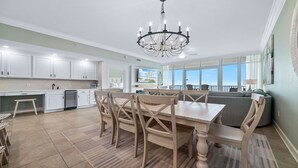 A spacious kitchen with white cabinets, a dining area with wooden chairs, and a large window overlooking a scenic view.