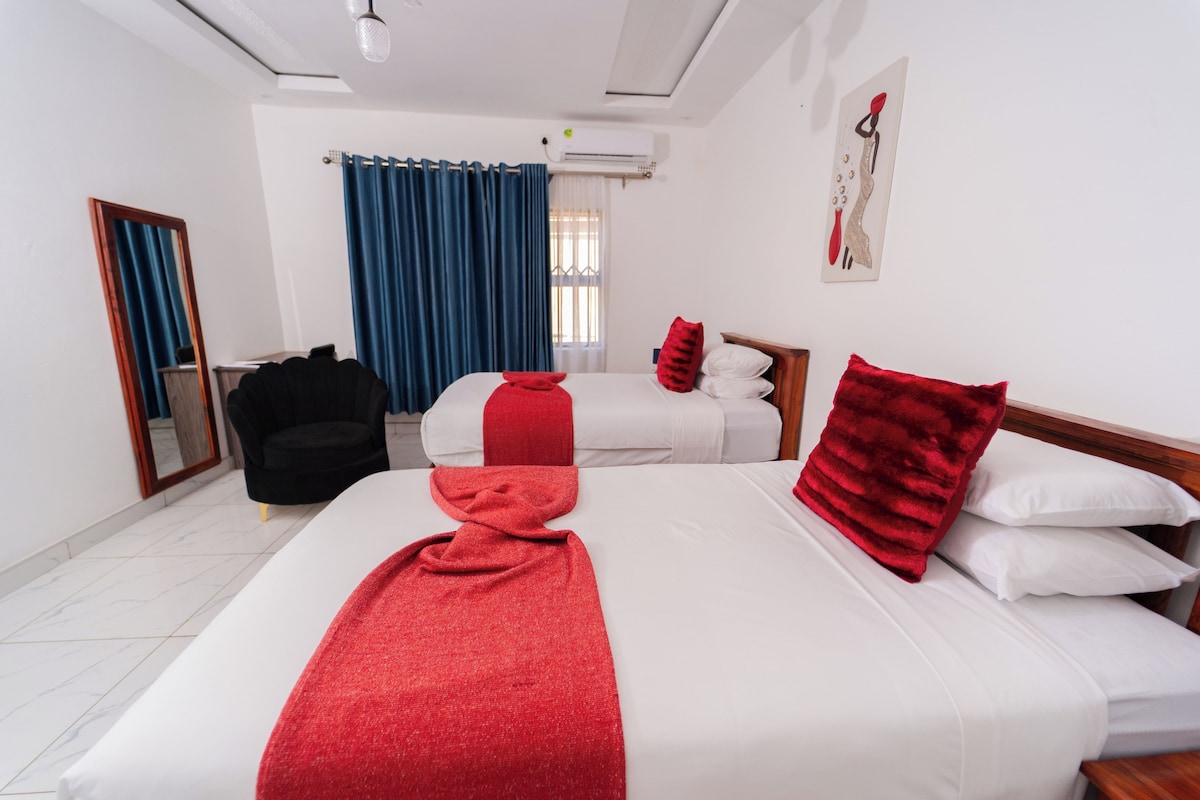 A hotel room with two beds, a mirror, a chair, and a painting on the wall.