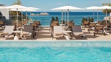 Una piscina al aire libre, sombrillas, tumbonas