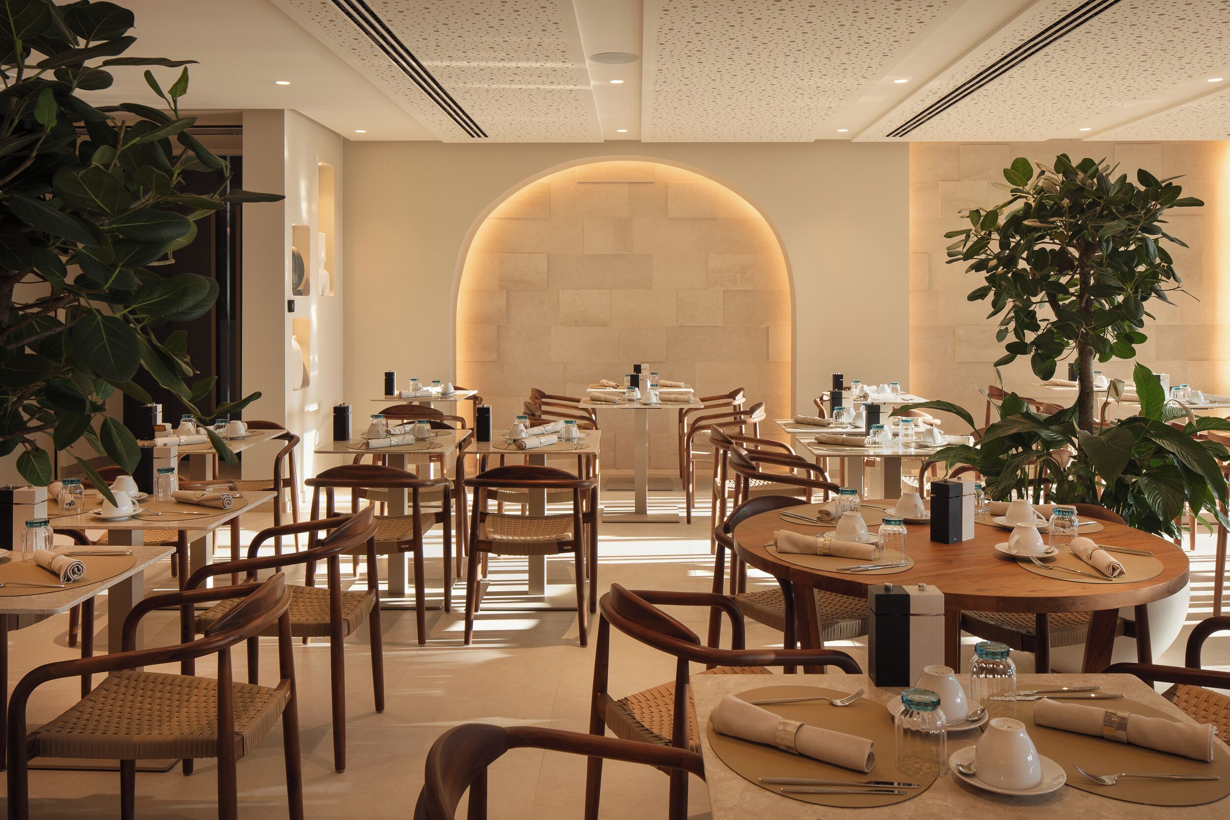Ein Restaurant mit runden Tischen, Holzstühlen und einer einladenden, gemütlichen Atmosphäre.