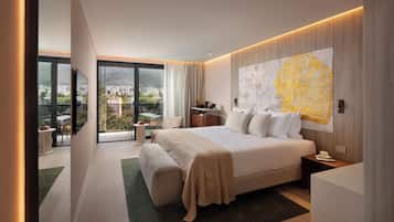 Habitación de hotel moderna con una cama grande, una obra de arte con un mapa, un balcón con vistas y un escritorio con una silla.