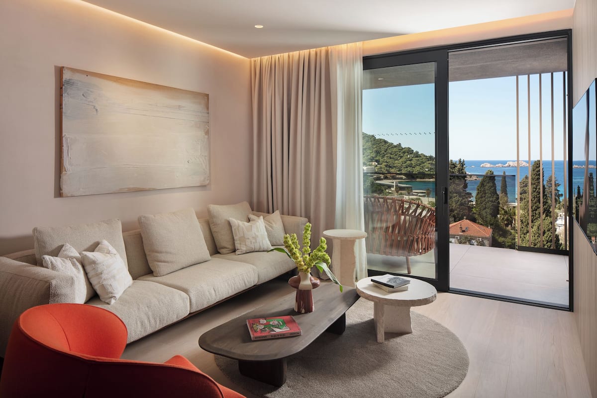 A modern living room with a sofa, coffee table, and a view of the sea.