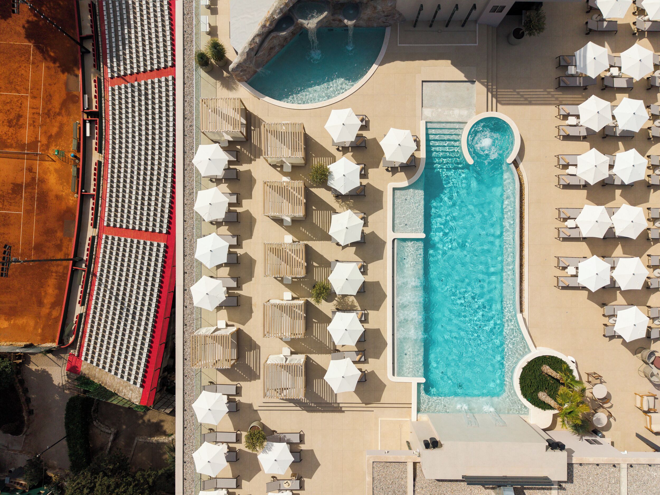 Luchtbeeld van een resort met een groot zwembad, ligbedden en parasols.