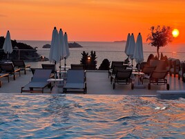 Una piscina al aire libre, sombrillas, sillones reclinables de piscina