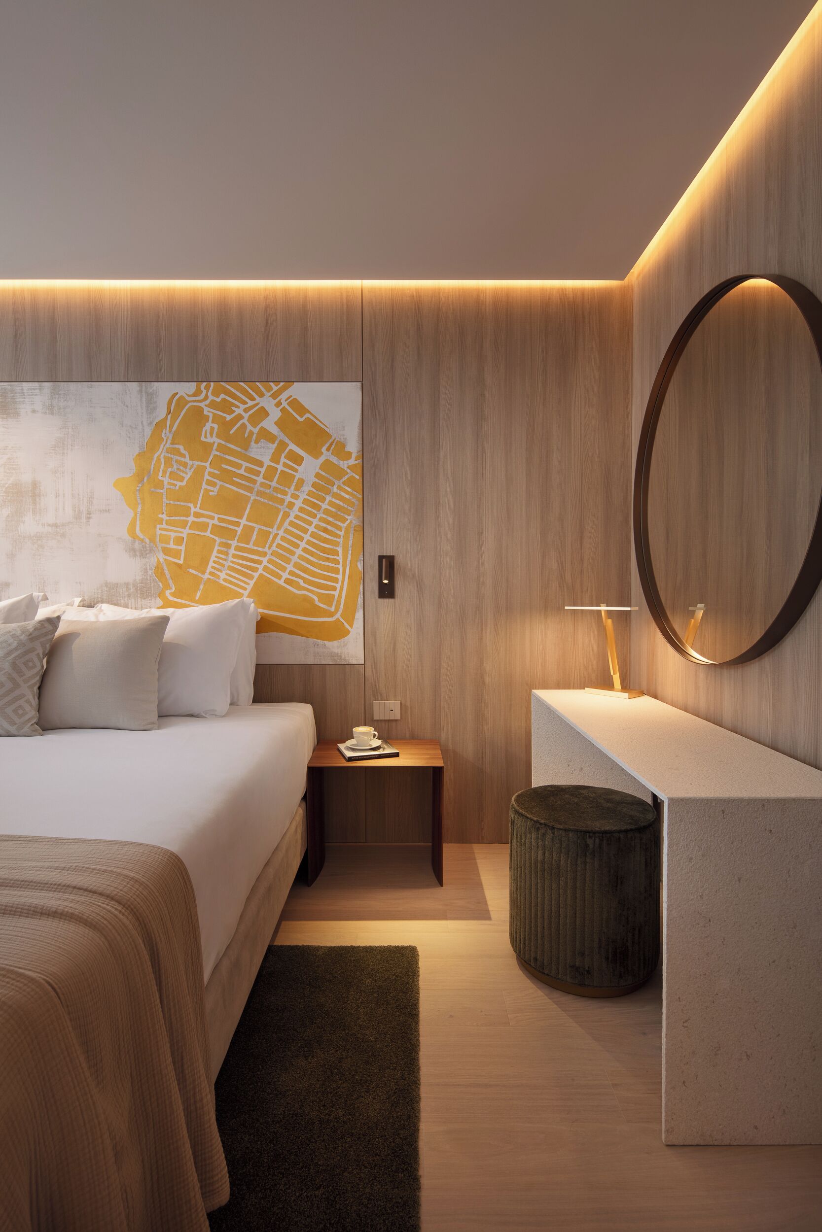 Una habitación de hotel moderna con una cama, una mesita de noche, un espejo redondo y un mapa colgado en la pared.