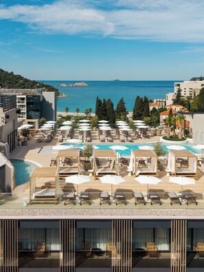 Una piscina al aire libre, sombrillas, sillones reclinables de piscina