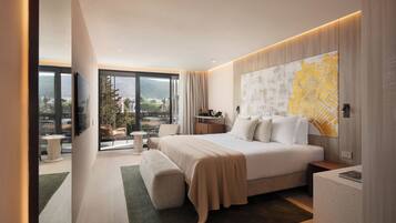 A modern hotel room with a large bed, a view of the outdoors, a map artwork on the wall, and a small side table.