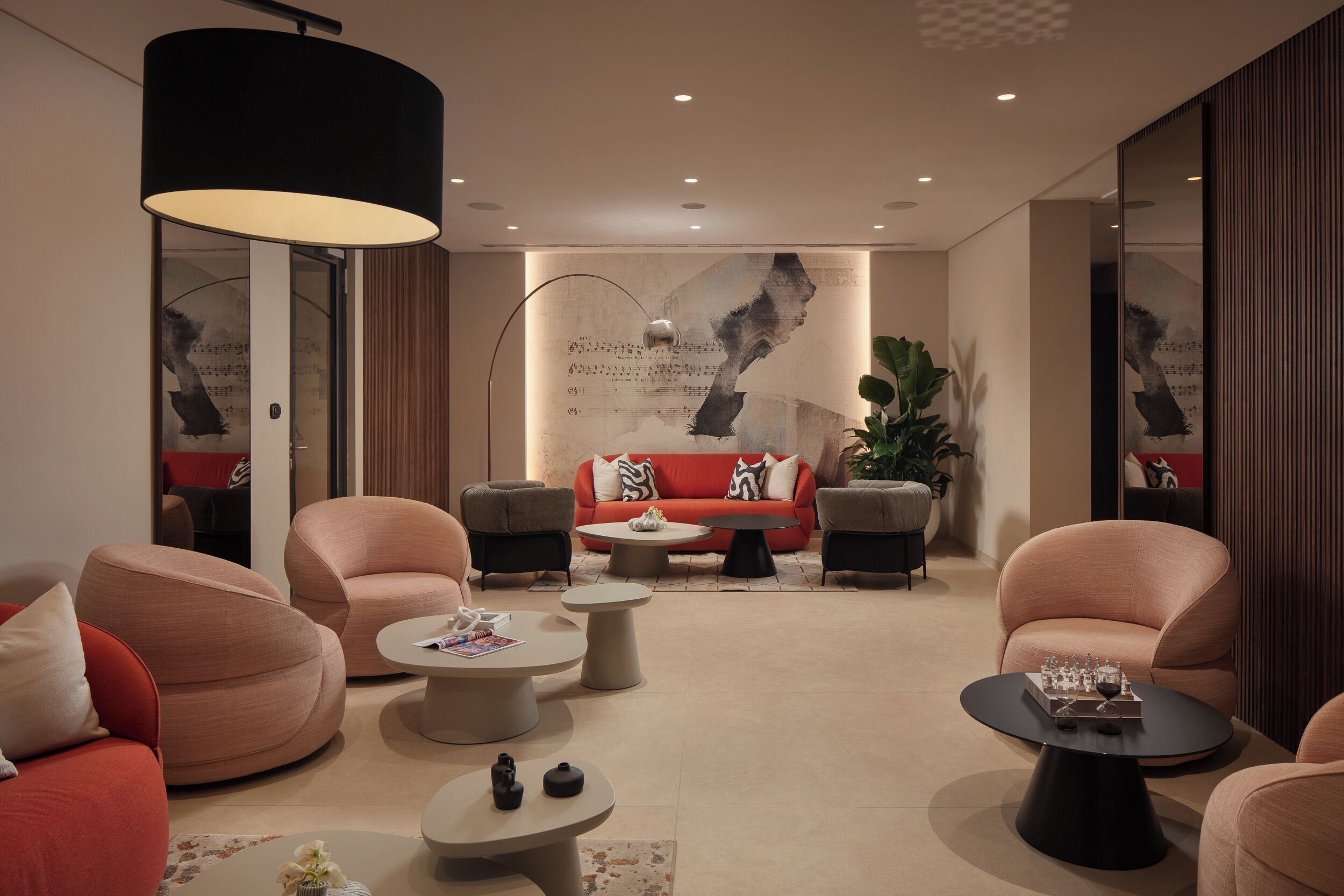 A modern living room with a red sofa, round coffee tables, and a large abstract painting on the wall.