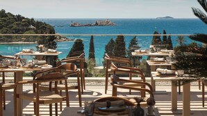 A terrace with tables and chairs overlooking a coastal view with rocky formations and the sea. - Hotel Sumratin (Dubrovnik)