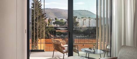 A balcony with a view of a cityscape, a table, and two chairs.
