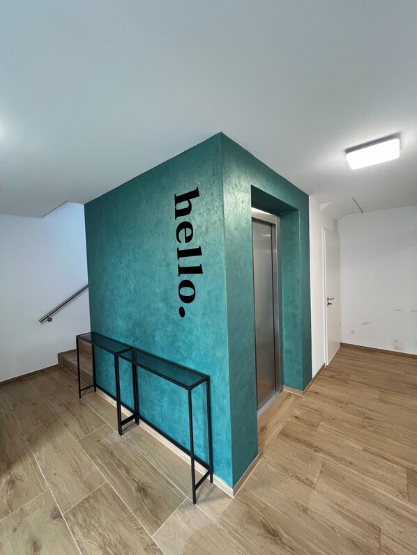 A modern interior with teal accent walls, a wooden floor, and a bench. - Modern cozy purple apartment (Bielefeld)