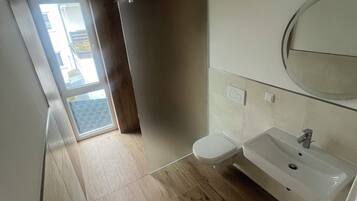 A modern bathroom with a wooden floor, a white sink, and a mirror above it.