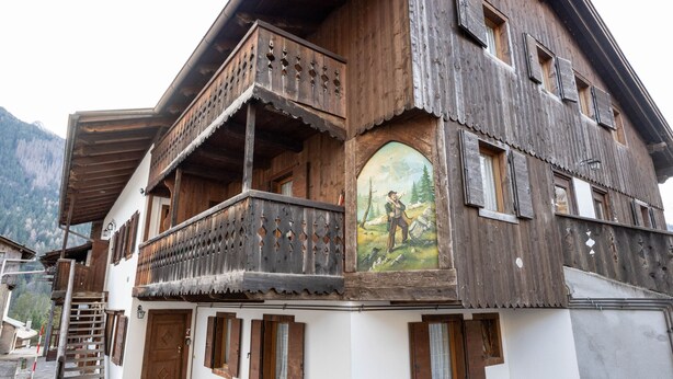 Ein traditionelles Holzhaus mit Balkon und Wandgemälde.