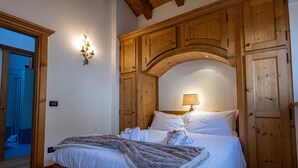 Ein Schlafzimmer mit einem hölzernen Kopfstück, einem Bett mit weißer Bettwäsche, einer Nachttischlampe und einem Holzschrank.