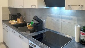 Une cuisine moderne avec des meubles blancs, une cuisinière noire et un four encastré.
