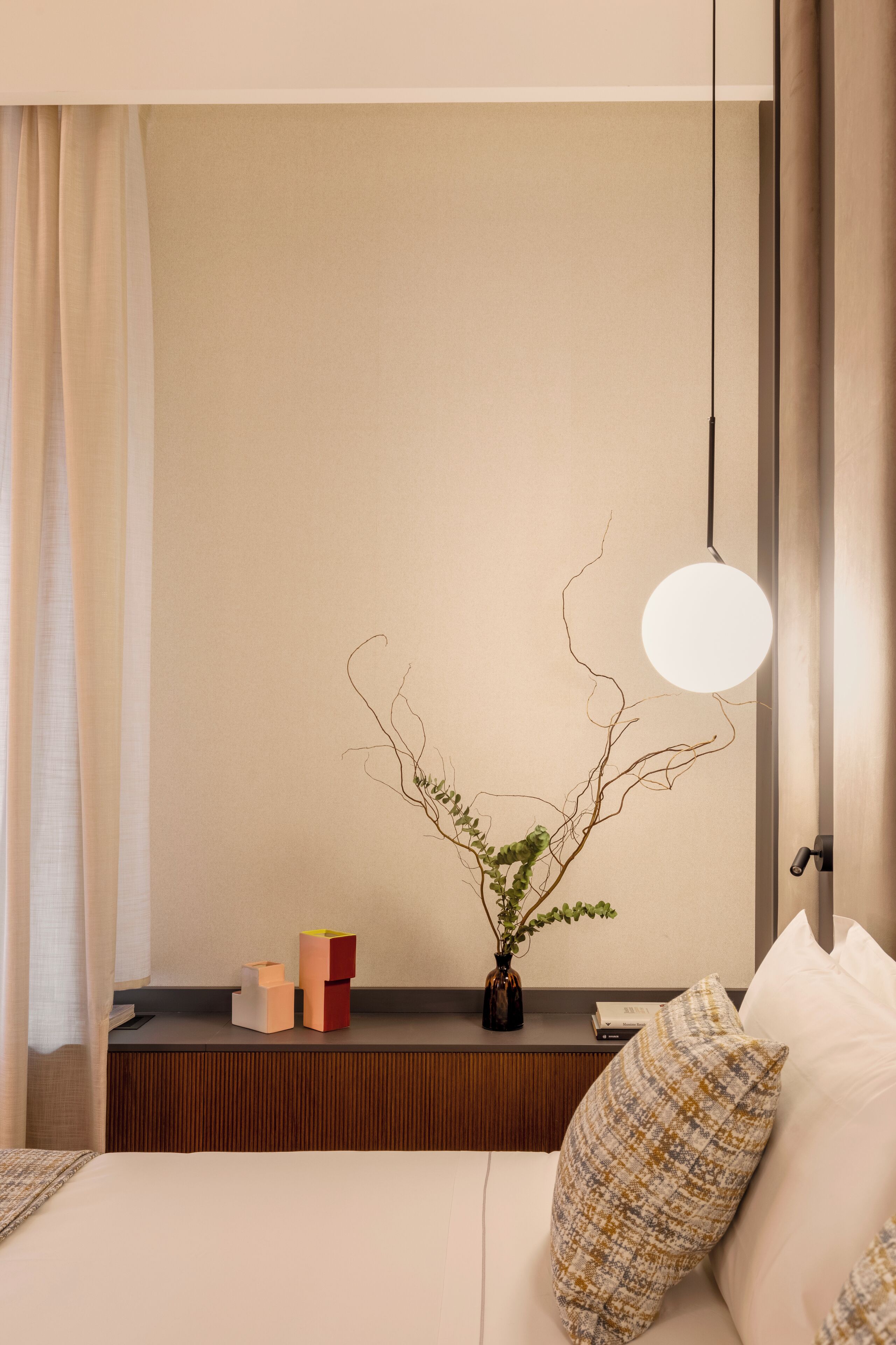 Una camera d'albergo ben ordinata con un letto, un comodino e una lampada a parete.