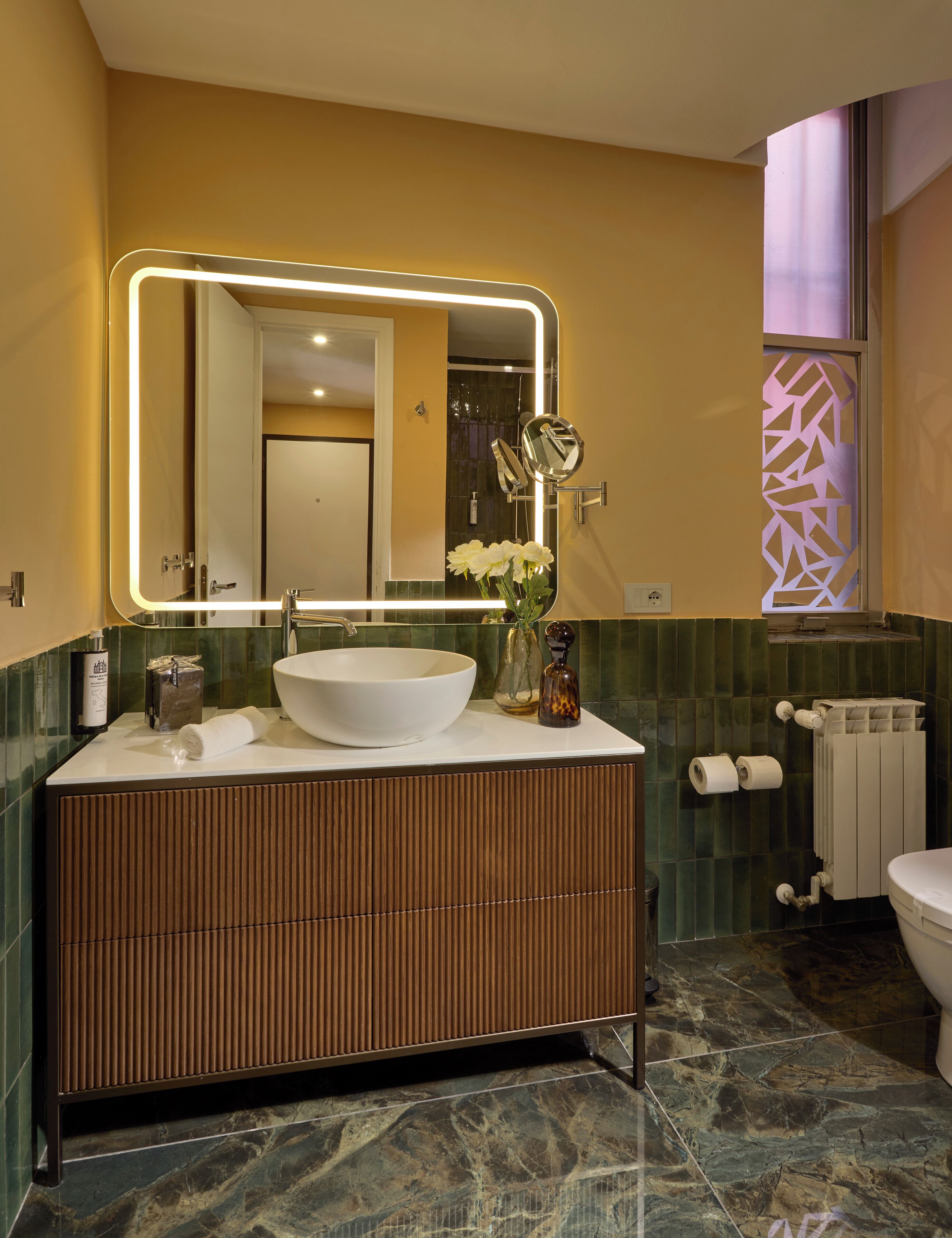 Ein modernes Badezimmer mit einem großen Spiegel, einem weißen Waschbecken und einer Toilette.
