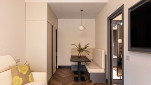 A narrow hallway with a sofa, a table with a plant, and a television mounted on the wall. - LUMERA STAY - Brera (Milan)