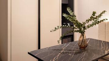A modern dining area with a marble table, black metal legs, and a hanging light fixture.