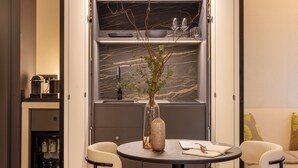 A compact dining area with a round table, four chairs, a vase with branches, and a built-in wine rack above the table. - LUMERA STAY - Brera (Milan)