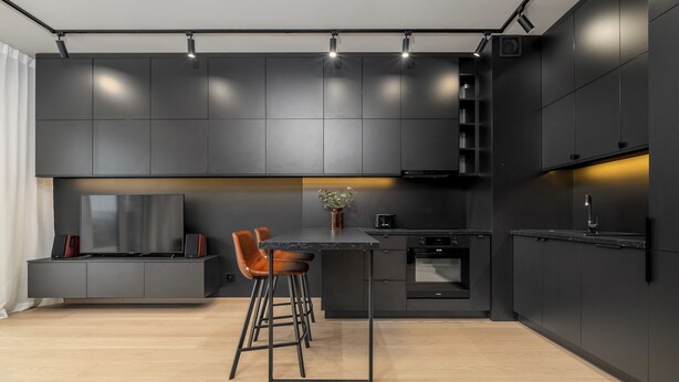 A modern kitchen with dark cabinetry, a central island, and bar stools.