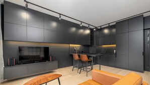 A modern living room with a large flat-screen TV, a wooden coffee table, and orange leather sofas.