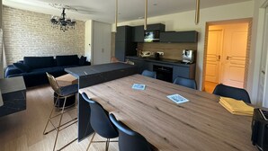 Een moderne keuken met donkere kasten, een centraal eiland en hanglampen.