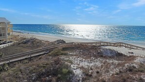 A beach with a wooden boardwalk leading to a building with a balcony. - 🌊Dog Friendly-Steps2Bch-Beach Views-Sea Cliff A5 Sunset Shores (Cape San Blas)