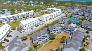 A coastal residential area with multi-story buildings, a tennis court, and a view of the ocean. - 🌊Dog Friendly-Steps2Bch-Beach Views-Sea Cliff A5 Sunset Shores (Cape San Blas)