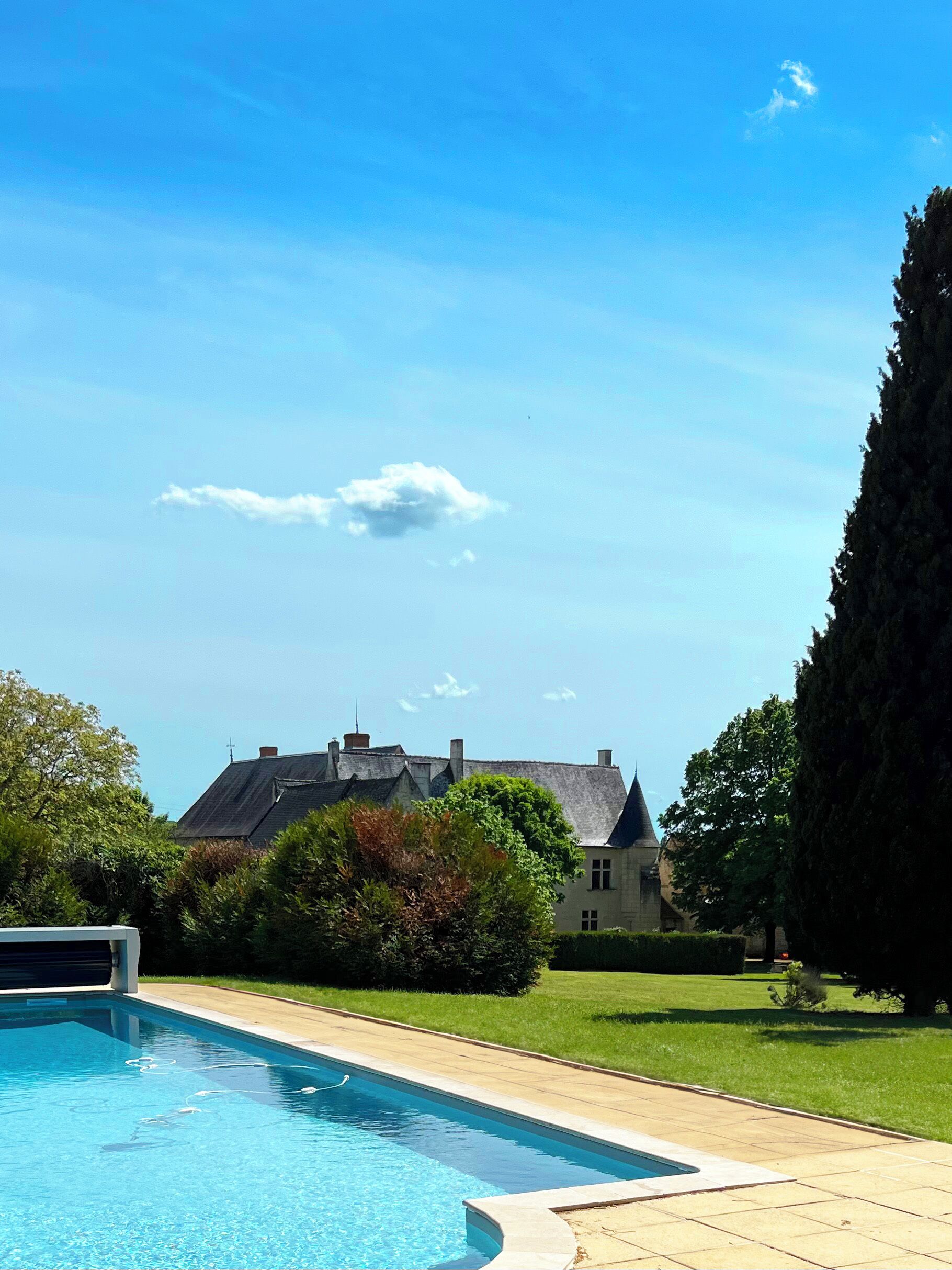 A swimming pool with a clear blue sky and a house in the background.