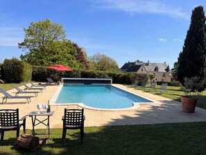 A rectangular swimming pool with a tiled deck, surrounded by lounge chairs and a table with glasses and a bottle. - Loire Valley Château with Pool & Vineyards near Saumur & Chinon (Beaumont-en-Véron)