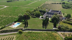 Luftaufnahme eines Weinbergs mit Schwimmbad und einem großen Haus, umgeben von Bäumen.